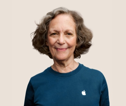Portrait of a smiling Apple Retail team member with wavy, dark grey hair.