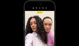 iPhone 18 Pro negro, de frente, que muestra dos personas con la funcionalidad de seguimiento facial, demostración de la cámara frontal Center Stage