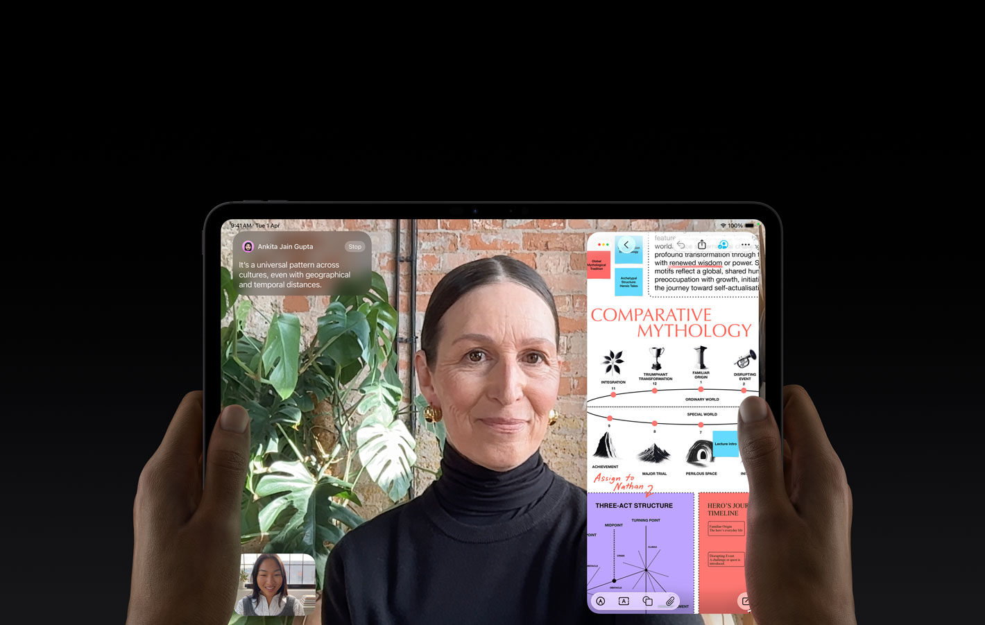 iPad Pro, front exterior, space black colour, left and right hands holding in landscape orientation, rounded corners, black display bezel, display showing a FaceTime conversation being live translated and an educational app showing a presentation of 'Comparative Mythology' with text, diagrams and handwritten notes