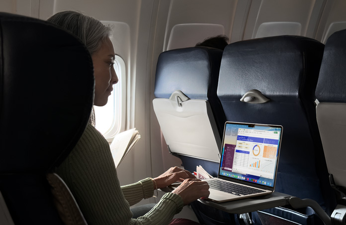 Osoba siedząca w samolocie i pracująca na MacBooku Air