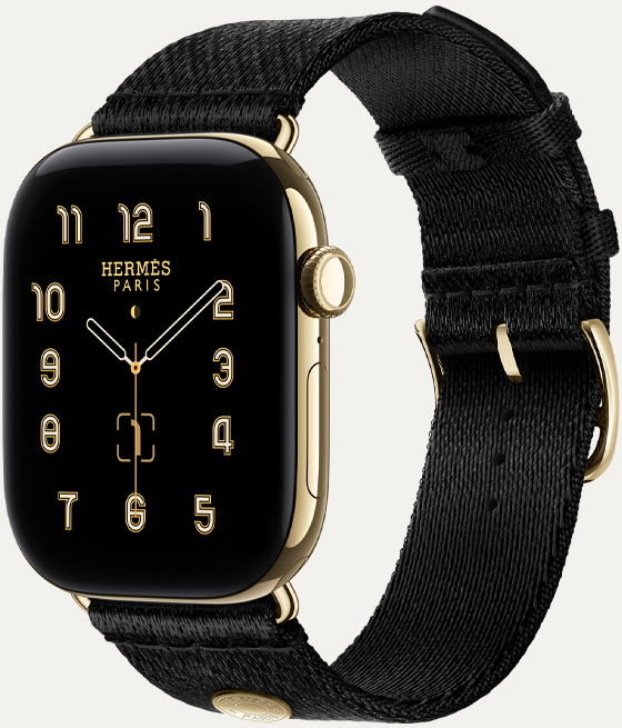 Apple Watch Hermès Series 12, Clou de Selle analogue watch face (hour, minute and second hands, complications: lunar phase, date), titanium case, radiant gold colour, right side exterior, Digital Crown, side button, paired with Noir Satin Clou de Selle strap, smooth black satin webbing with radiant gold hardware that matches the watch case