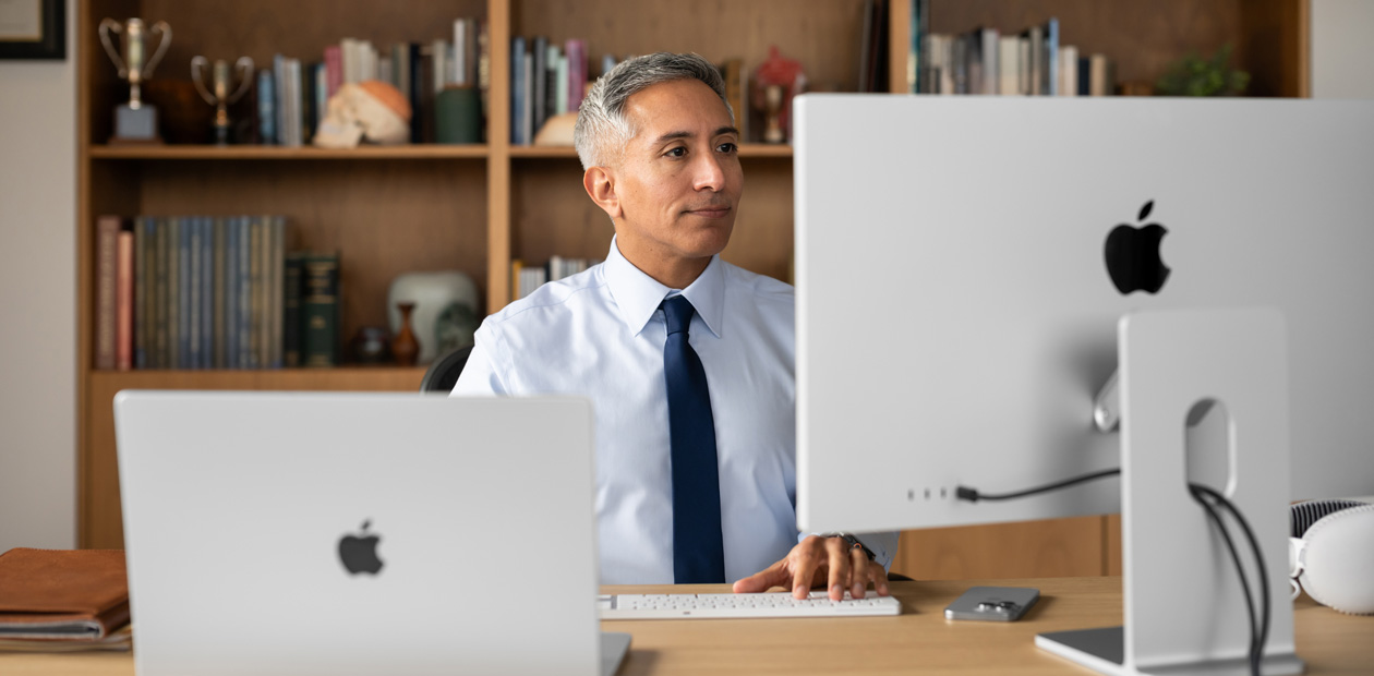 デスクでiMacとMacBook Proを見ている医療従事者