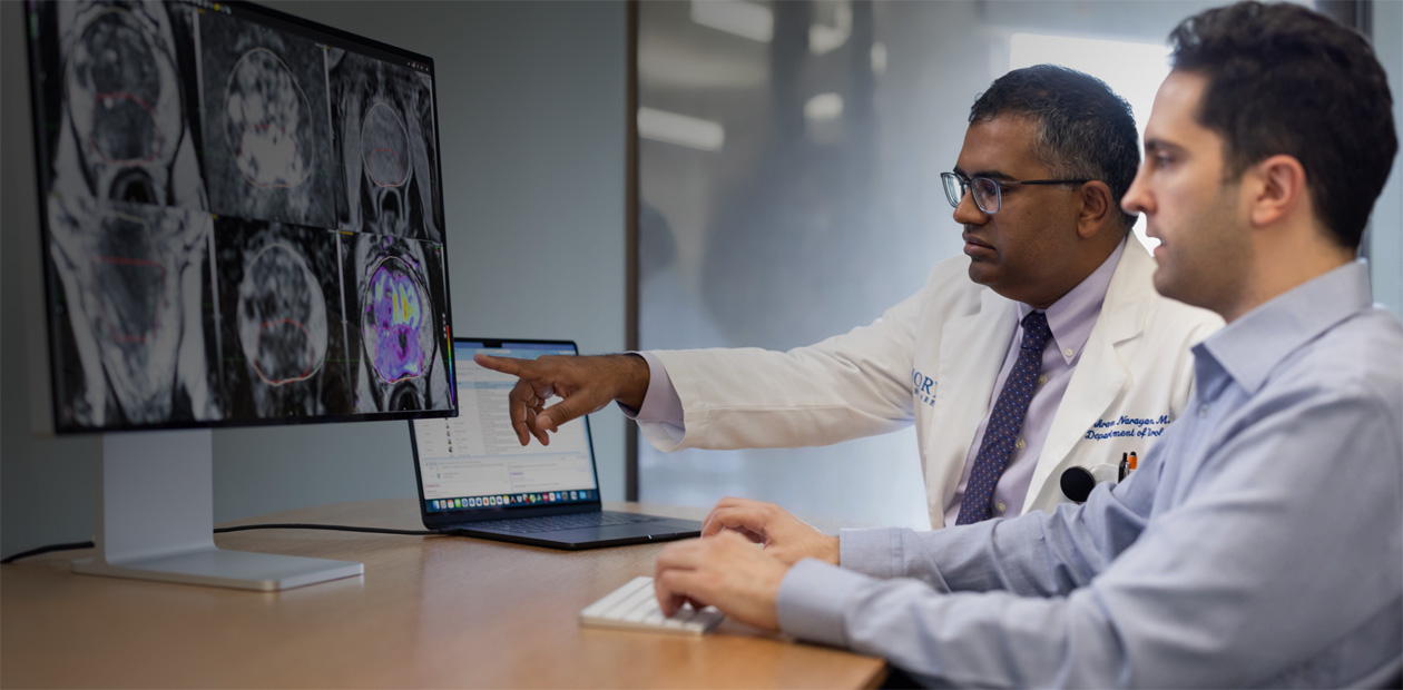 Dois médicos observando imagens de radiologia em um iMac.