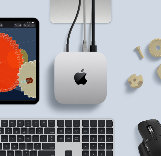 iPad displaying detailed STEM objects, Mac mini central with power cable attached, Studio Display stand partially visible, connected via USB‑C, Magic Keyboard with Touch ID, and Logitech mouse