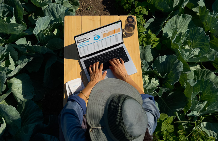 Una persona sentada al aire libre usa un MacBook Pro configurado con opción de pantalla con acabado nanotexturizado, donde se aprecia la reducción del reflejo