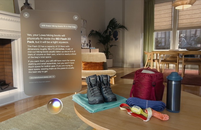Answer to a query for Siri about packing camping essentials hovers above Siri orb on left side of screen, walking boots, ropes, backpack, water bottle and head lamp sit on table on right side of screen