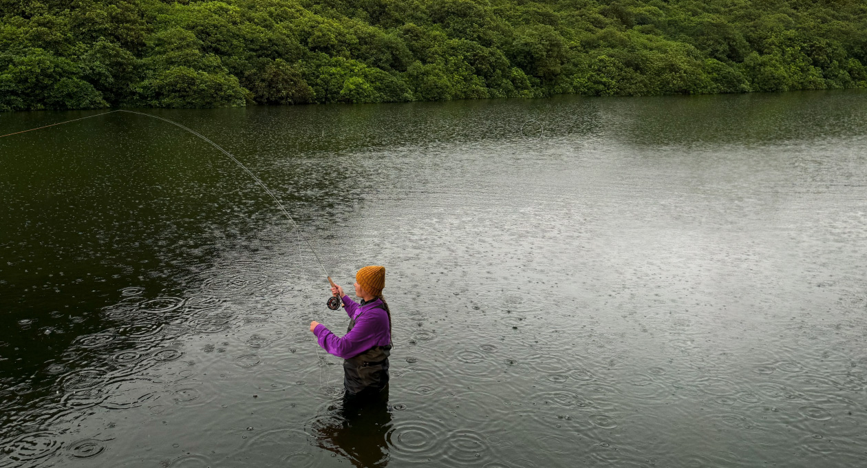 Photo of a woman fly-fishing on a lake, Pixelmator Pro tool removing unwanted object in the background being highlighted in yellow